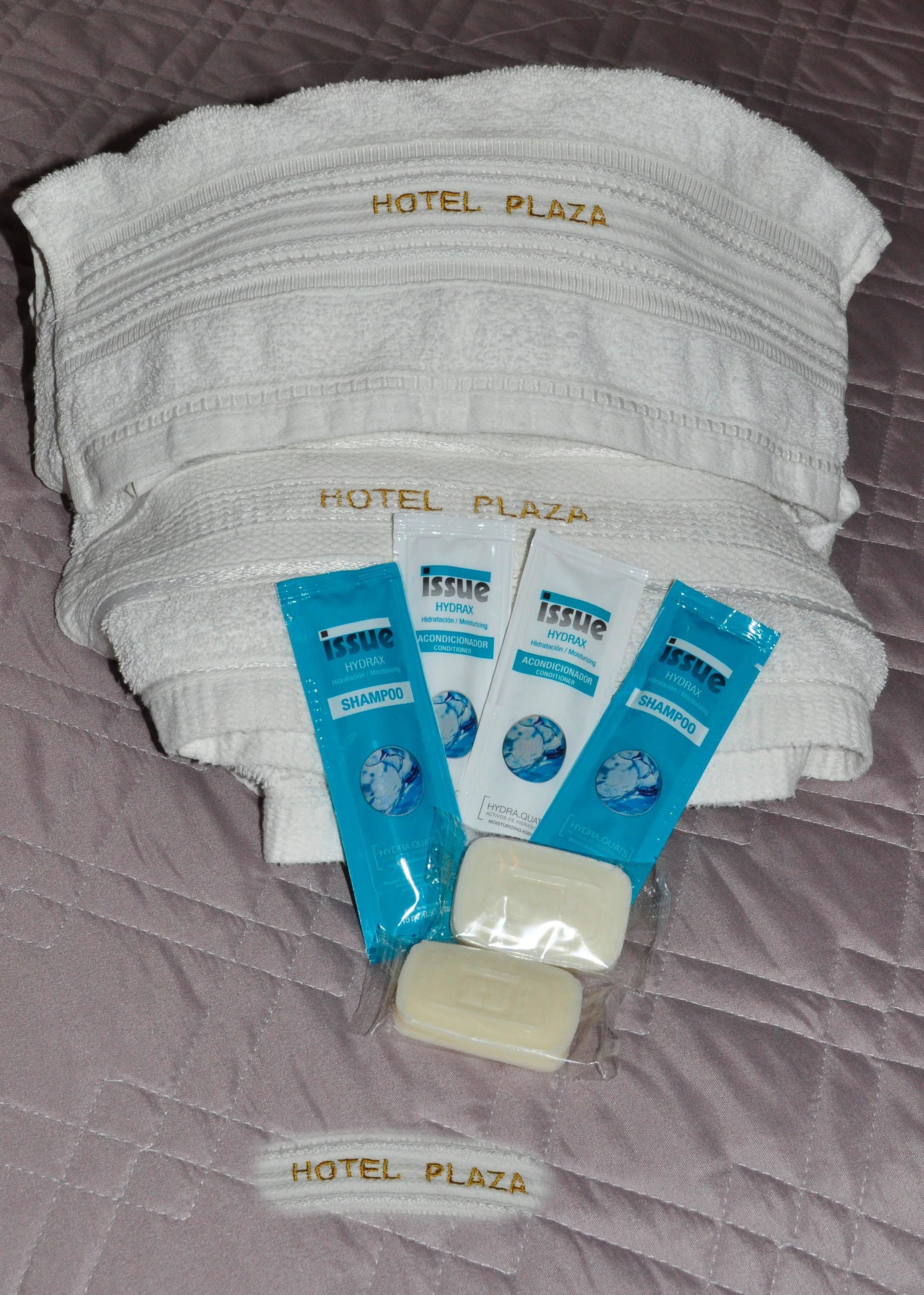 Una cama de hotel con toallas blancas y artículos de aseo, incluyendo champú y acondicionador.