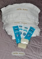 Una cama de hotel con toallas blancas y artículos de aseo, incluyendo champú y acondicionador.