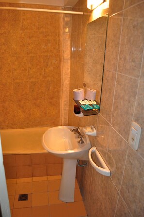 Un baño con bañera, lavamanos y espejo.