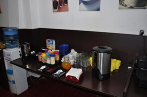 Una barra de desayuno con dispensador de agua, cafetera y diversas opciones de alimentos.