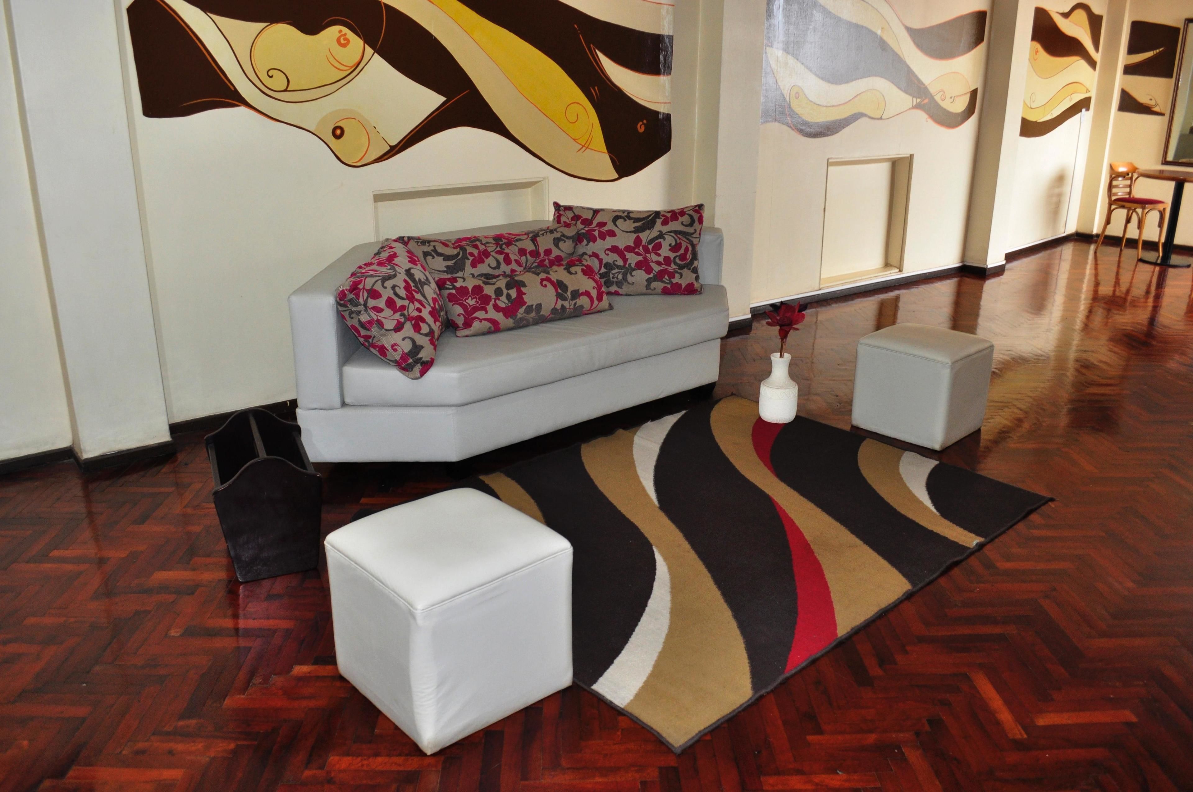A modern living room with a sofa, ottomans, and a patterned rug.