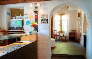 A reception desk with a computer, a vase with flowers, and various informational posters on the wall.