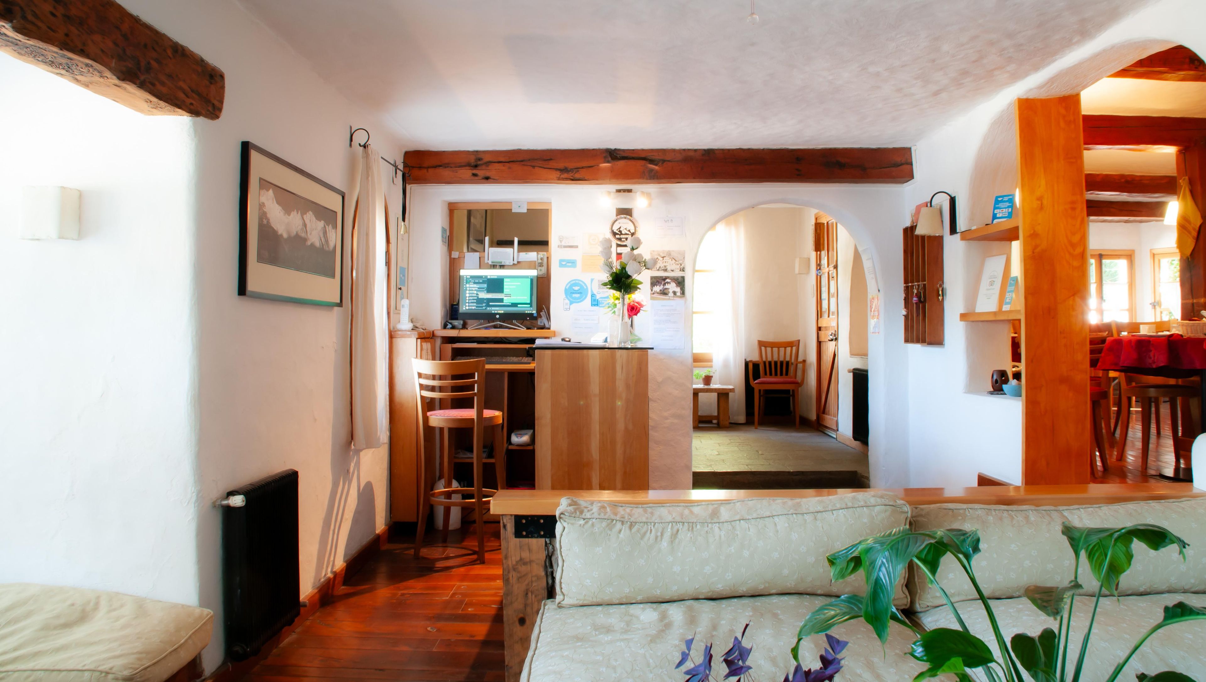 Un espace de vie chaleureux avec un plafond en bois, une table à manger avec des chaises, un coin cuisine équipé d’un ordinateur et un canapé.