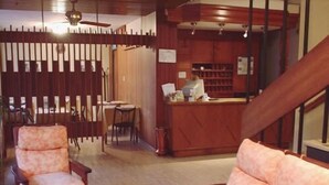 A cozy living room with a wooden reception desk, a staircase, and a dining area. - Hotel Dali (San Rafael)