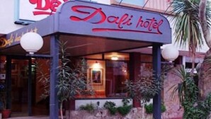 The exterior of the Dali Hotel with a prominent sign, potted plants, and a red brick pathway leading to the entrance. - Hotel Dali (San Rafael)