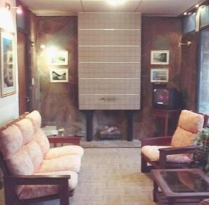 A living room with a fireplace, two armchairs, a coffee table, and framed pictures on the walls.