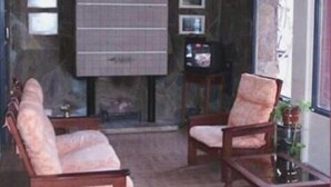 A room with a fireplace, two cushioned chairs, a wooden coffee table, and a large window with a view. - Hotel Dali (San Rafael)