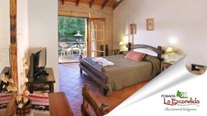 Un dormitorio con cama, mesitas de noche, televisión y vistas al patio exterior.