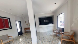 Un vestíbul d'hotel amb rajoles de terra estampades, una taquilla d'adreça i zones d'estar.