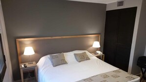 Habitació d'hotel amb un llit gran, dues taules de nit amb làmpades, un telèfon i un armari.