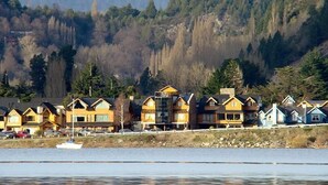 A row of coastal houses with a boat in the foreground. - Valldemossa Apart Hotel (San Martín de los Andes)