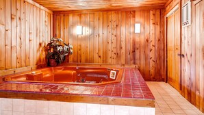 Una cabaña de madera con jacuzzi, piso de baldosas y paredes de madera.