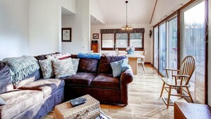 Un salón amplio con un sofá de cuero, una mesa de comedor de madera y un gran ventanal con vistas al exterior.