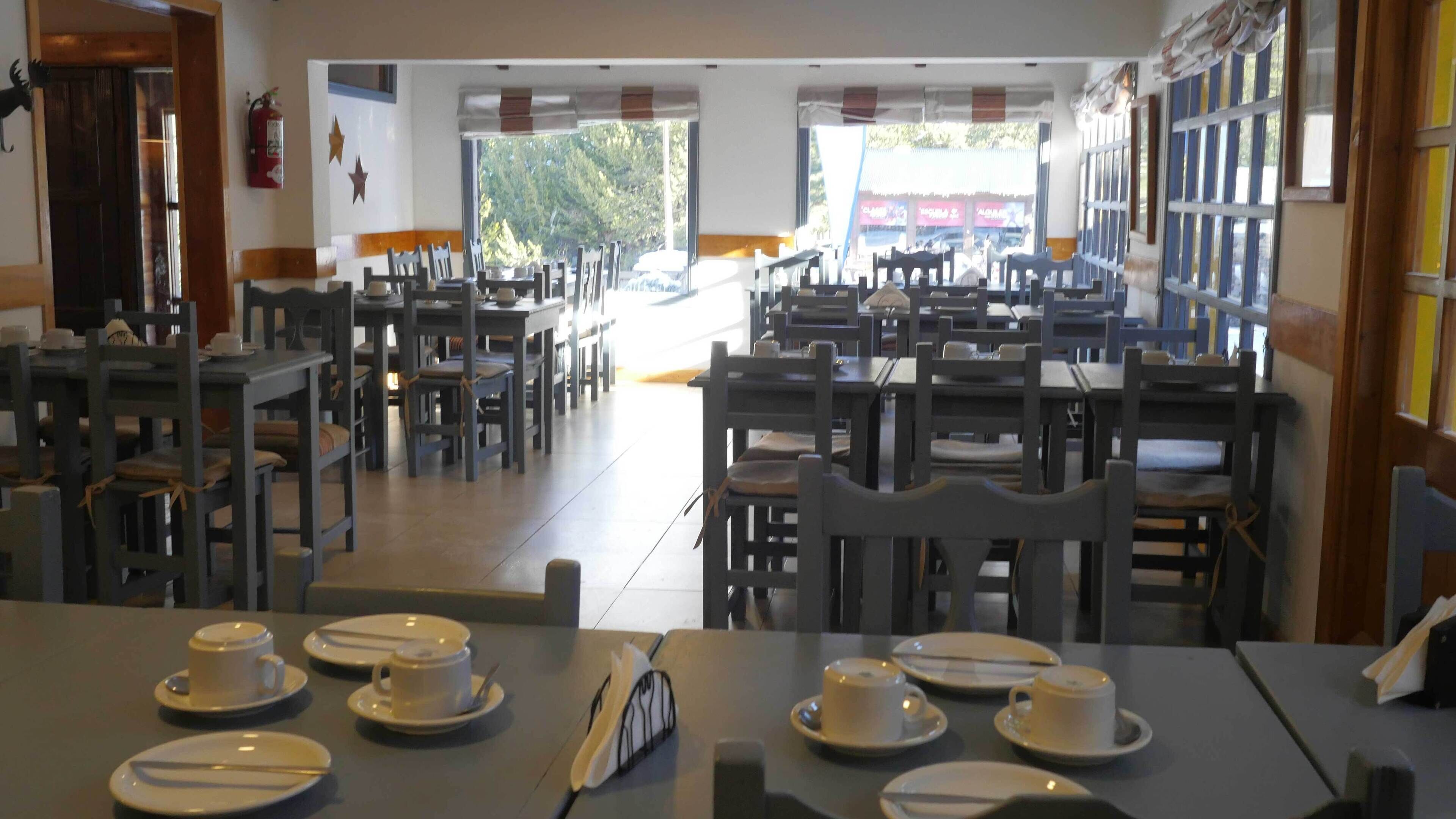 A restaurant with multiple tables and chairs, some with plates and cups set.
