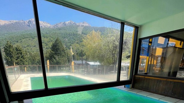 A large indoor swimming pool with clear views of mountains and trees through large windows. - Complejo Base 41 (San Carlos de Bariloche)