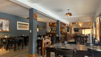 A restaurant interior with wooden tables and chairs, a bar area, and a counter with a menu.