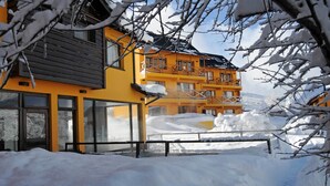 A yellow building with multiple balconies and large windows, surrounded by snow. - Complejo Base 41 (San Carlos de Bariloche)