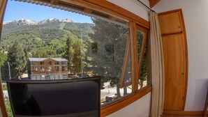 A room with a large window offering a view of a mountain and a building. - Complejo Base 41 (San Carlos de Bariloche)