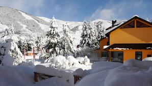 A snow-covered mountain landscape with a yellow building featuring large windows and a sloped roof. - Complejo Base 41 (San Carlos de Bariloche)