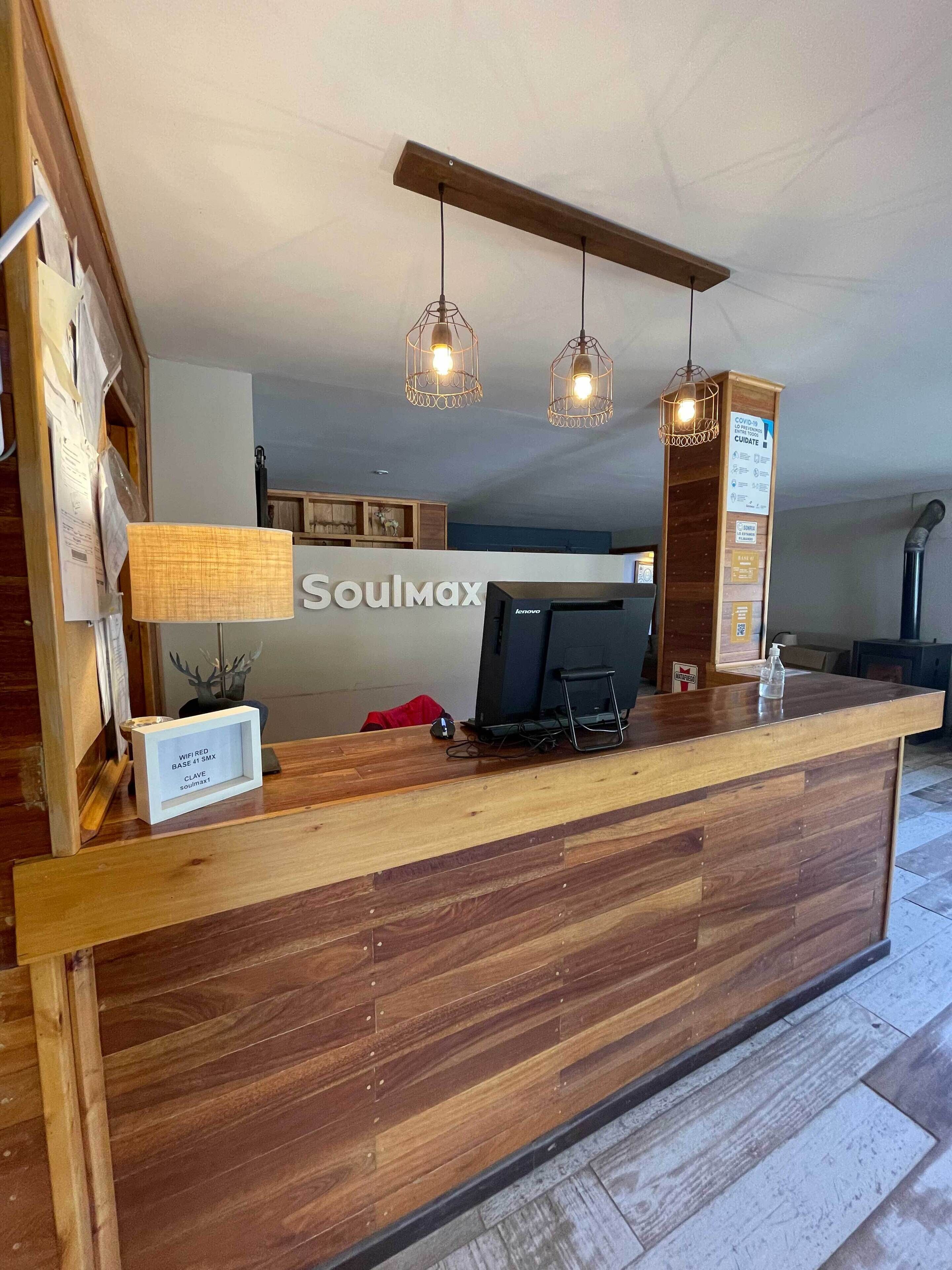 A wooden reception desk with a sign reading "Soulmax" and a mounted computer monitor.