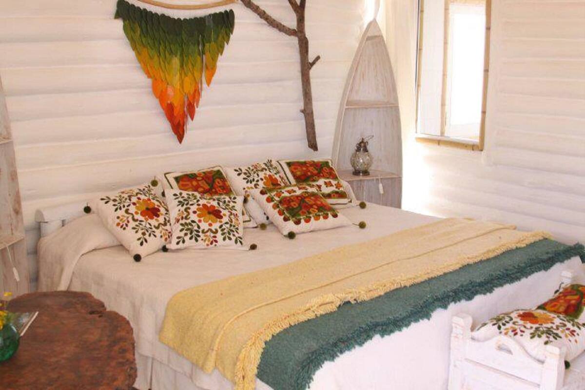 Uma cama com almofadas florais, um adorno pendurado e uma janela com vista.