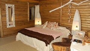 Une chambre confortable dans un chalet en bois, avec un lit, deux lampes fixées au mur, un miroir et une table de chevet en bois.