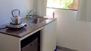 A compact kitchen with a sink, a kettle, and a window with curtains. - Hotel Sanguinetti (Victoria)