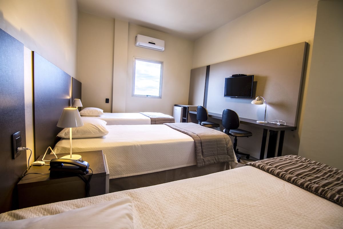 Habitación de hotel con dos camas, un escritorio, una silla, un televisor y una ventana.
