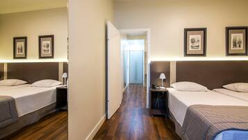 Quarto de hotel com duas camas, piso de madeira e quadros nas paredes.