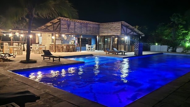 Un área de piscina con una casa, mobiliario exterior y un bar.