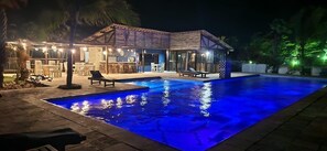 Uma área de piscina com casa, mobiliário de exterior e bar.