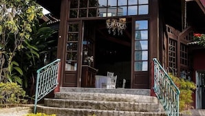 Un bâtiment traditionnel en bois, doté d’un porche, d’un escalier et d’une balustrade.