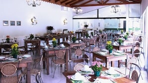 Un restaurant spacieux avec des tables et des chaises en bois, de grandes fenêtres et un éclairage décoratif.