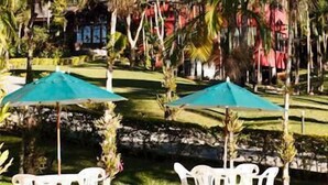 Un complexe hôtelier tropical avec des palmiers, un ciel dégagé et une vue sur une chaîne de montagnes.