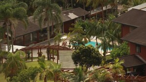 Un complexe hôtelier comprenant plusieurs bâtiments, une piscine et de nombreux palmiers.
