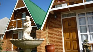A building with a green roof, brick walls, and a wooden door. - Cabañas Las Brisas (Puerto Madryn)