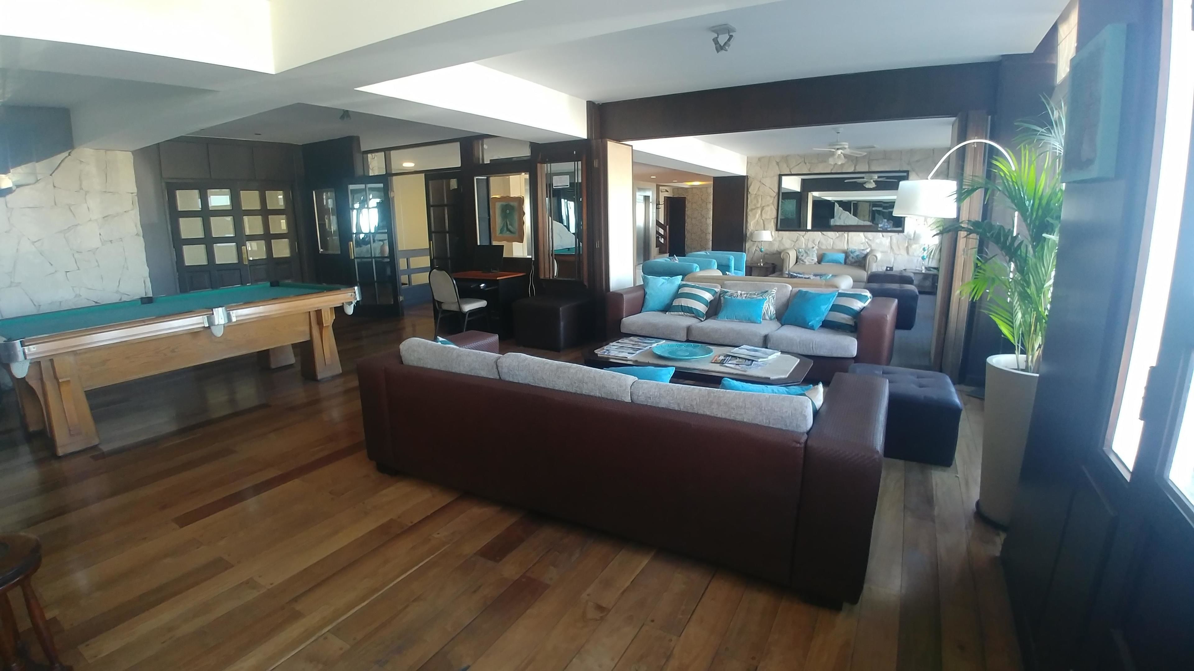 A spacious living room with a pool table, a sofa set, and a large mirror.