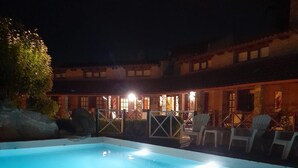 Una piscina con sillas de descanso y un edificio al fondo.