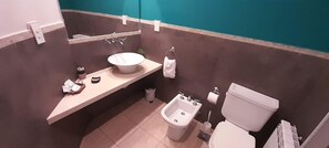 A bathroom with a sink, mirror, towel rack, bidet, toilet, and a trash bin. - Curahue Apart Hotel (Tandil)
