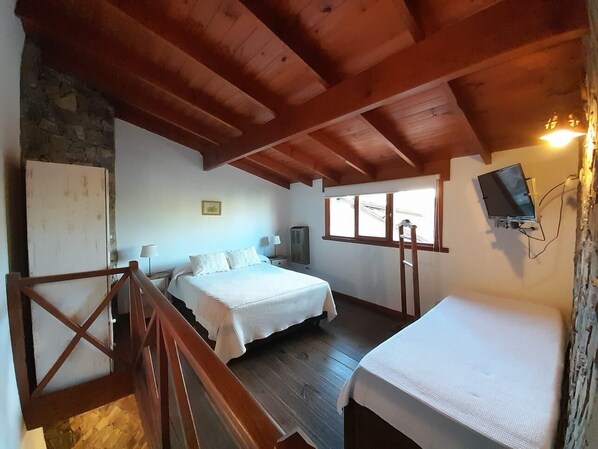 A room with two beds, a TV, and a stone wall. - Curahue Apart Hotel (Tandil)