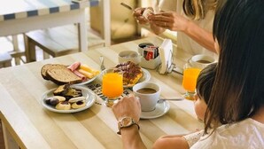 Una mesa de desayuno con diferentes alimentos, una taza de café y un vaso de zumo de naranja.
