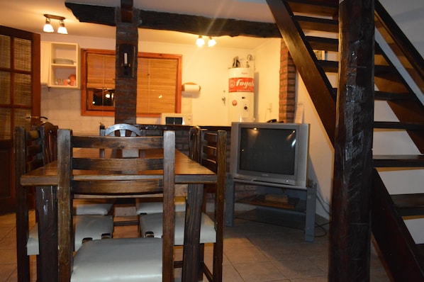 Un comedor con una mesa y sillas de madera, un televisor y un dispensador de agua.