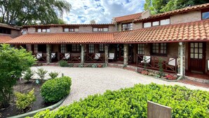 Un patio con techo de tejas, pilares de piedra y mobiliario exterior.