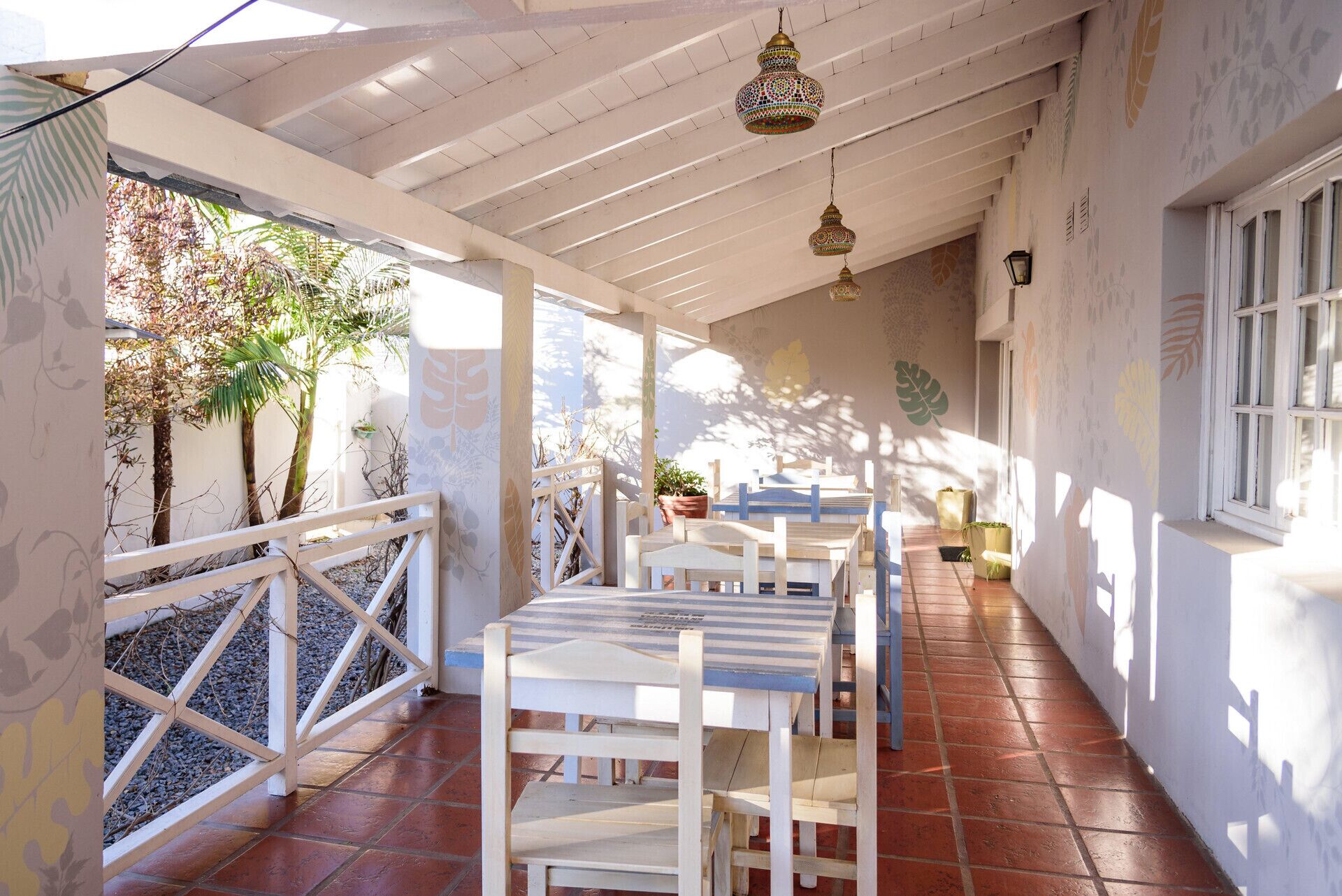 Eine Terrasse im Freien mit weißer Möbel, Fliesenboden und hängenden Lichterketten.