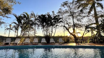 Una piscina al aire libre, sillones reclinables de piscina