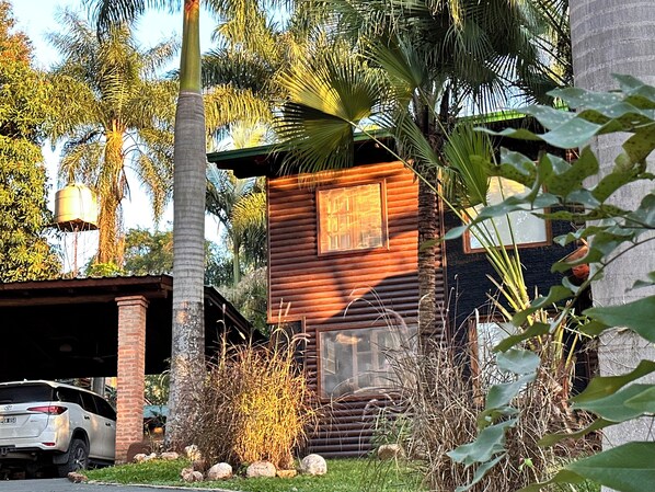 A rustic cabin with a wooden exterior, surrounded by lush greenery and palm trees. - Costa del Sol Iguazú (Puerto Iguazú)