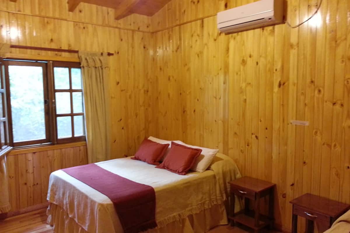 Une pièce en bois avec un lit, une petite table et un appareil de climatisation.