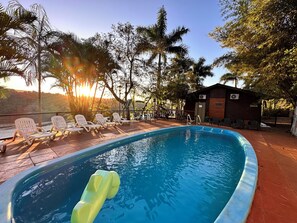 A swimming pool with lounge chairs, surrounded by trees and a small building. - Costa del Sol Iguazú (Puerto Iguazú)