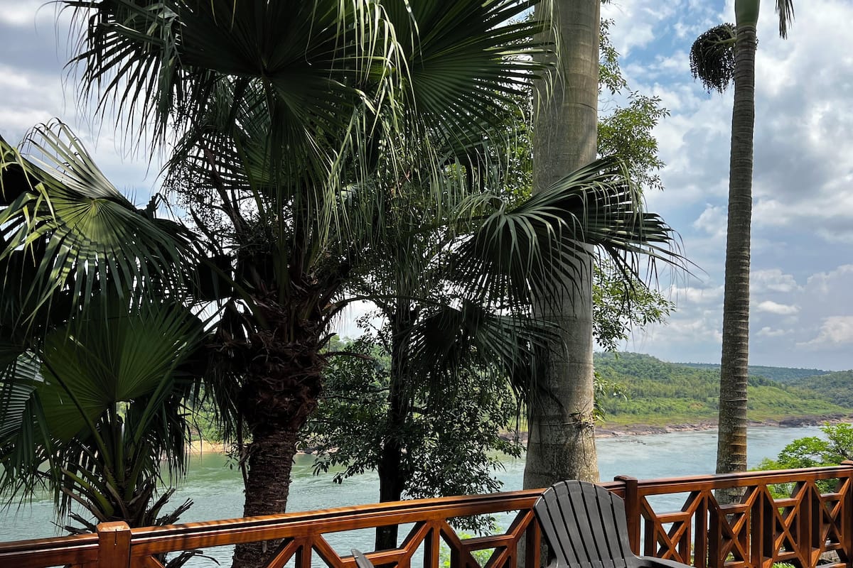 Une terrasse en bois offrant une vue sur une rivière et des collines.