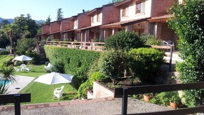 Un hotel con fachada de ladrillo, mobiliario exterior y zona de piscina.